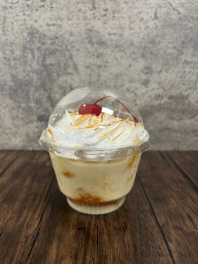 Tres leches dessert in clear cup with whipped cream and cherry topping